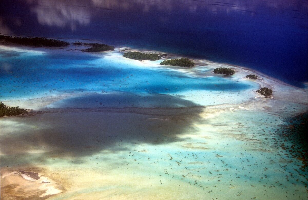 Atoll de Rangiroa vu du ciel, motu de sable blanc et lagon turquoise bordé de récif corallien