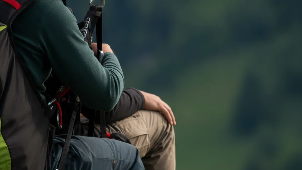Détail d'une sellette de parapente biplace, mains libres pendant le vol